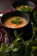 Two black plates with fresh homemade made split pea soup on dark background