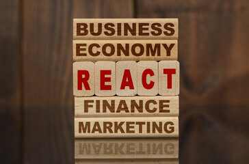 Wooden blocks with the text - Business, Economy, Finance, Marketing and REACT