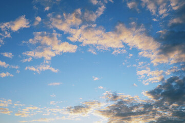 Blue sky, light and dark clouds at sunset. Cloudscape background or wallpaper. End of a sunny summer day