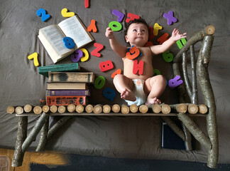 a funny little child with books and letters waved his hands and looks up to knowledge. background...