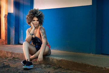 Beautiful happy African American woman enjoying life and having fun with hairstyle on city streets.