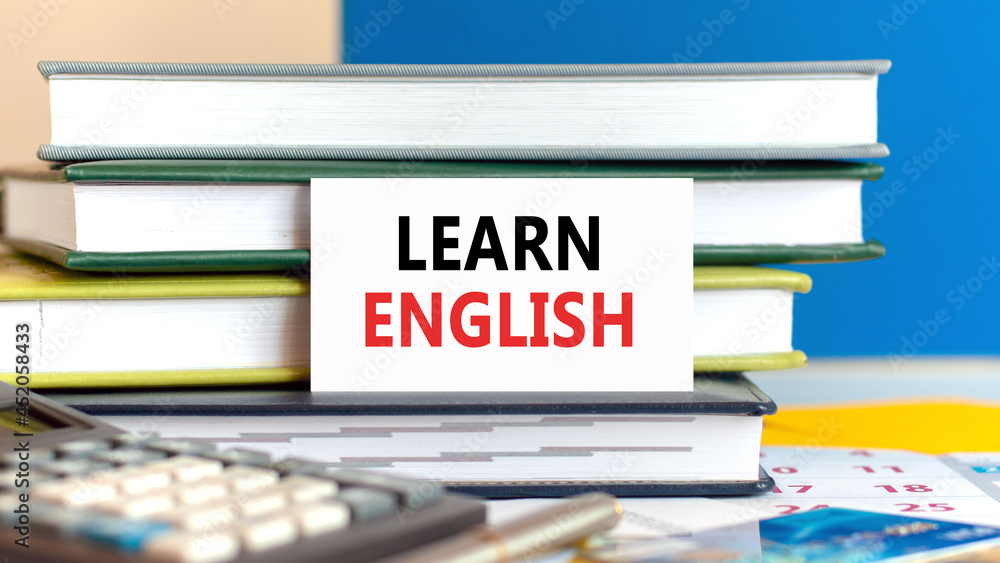 Poster white card with the text learn english stands against the background of books stacked blue backgroun