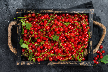 Organic Red currant berries in a wooden box. Black background. Top view