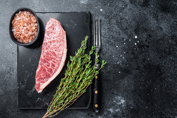 Wagyu raw sirloin steak, kobe beef meat on marble board. Black background. Top view. Copy space - obrazy, fototapety, plakaty