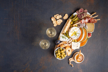 Snacks table with Italian snacks and wine in glasses. Brushetta, a kind of cheese board on a black background. Top view, flat layer - obrazy, fototapety, plakaty