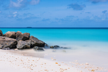 Fototapeta na wymiar Long exposure water of Indian ocean with stones on the Maldivian island. Crossroads Maldives, july 2021