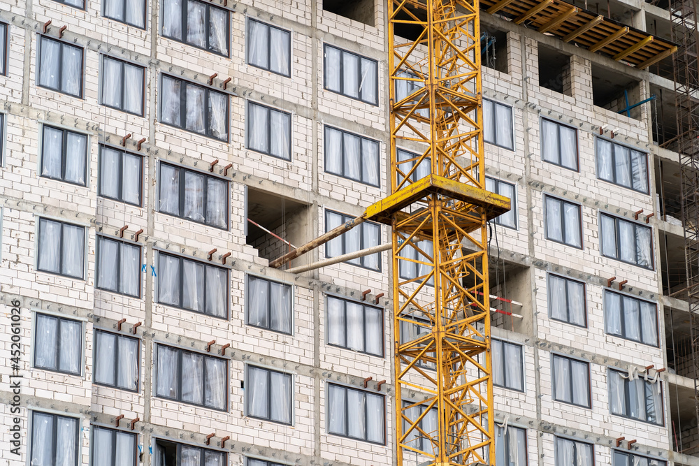 Poster view of frame part of metallic crane machinery attachment at windows of new residential building con