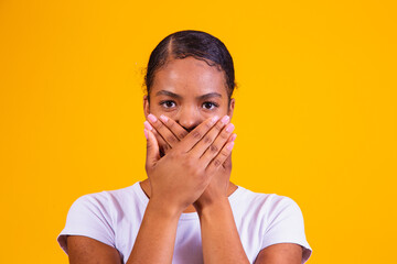 black woman on yellow background with her mouth closed in silence. Concept of prejudice, abuse and...