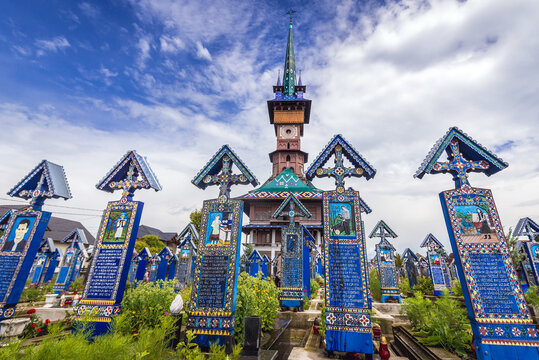 Sapanta, Romania - July 11, 2019: Wooden painted headstones and church on so called Merry Cemetery in Sapanta village