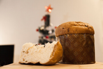 Panettone slice with Christmas tree
and blurry lights flashing in the background. Panettone concept. Christmas concept.