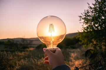 Man holding a light bulb during a sunset
