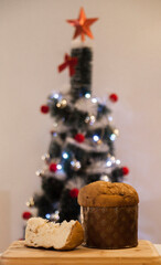 Panettone slice with Christmas tree
and blurry lights flashing in the background. Panettone concept. Christmas concept.