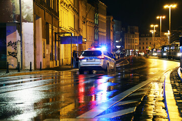 Radiowóz policji na sygnale w mieście wieczorem.