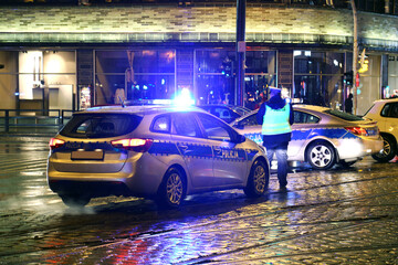 Radiowóz policji na sygnale w mieście wieczorem.
