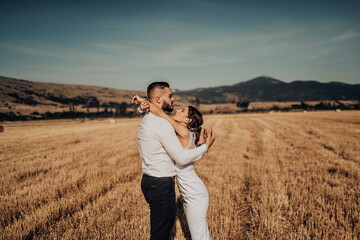 a young married couple in a large field enjoys the sunset. Selective focus