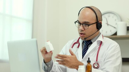 Doctor talks to patient via online video conferencing with laptop wearing headset. Explain about taking medications to treat illnesses.
