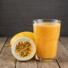 Passion fruit juice in a glass with fruits over wooden table
