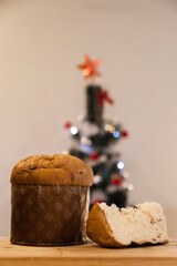 Panettone slice with Christmas tree
and blurry lights flashing in the background. Panettone concept. Christmas concept.