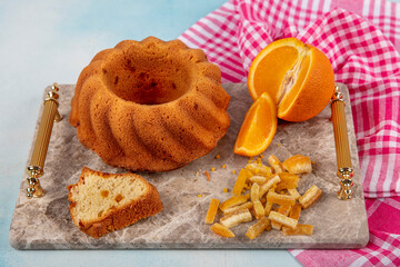 Homemade orange cake. Sliced fluffy chiffon cake with orange slices on cake plate. Light background, selective focus.