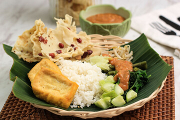 Nasi Pecel. Traditional Javanese Rice Dish of Steamed Rice with Vegetable Salad, Peanut Sauce Dressing, Tempeh, Tofu Beancurd, and Peyek Crackers. Pecel Madiun is Most Popular Variant