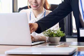 オフィスでパソコンを教える男性と若い女性