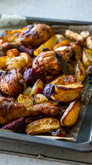 Grilled organic vegetables, potatoes, onions, beetroot, carrots, radishes with chicken legs on a baking sheet baked with herbs and spices. Top view.