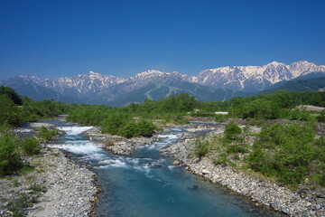 Fototapeta na wymiar 雪山が残る美しい田舎の川の景色