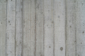 Flat bare concrete wall with many concrete form dimples and vertical grid lines of raw concrete...