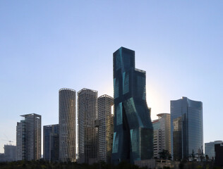 Fototapeta na wymiar Edificios altos de arquitectura moderna con el sol poniéndose a sus espaldas y el cielo azul