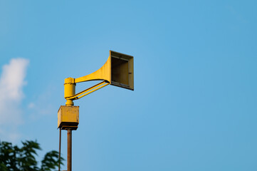 yellow warning siren with blue sky