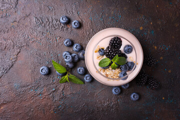 Obraz na płótnie Canvas Yogurt dessert with berries, oatmeal flakes and mint in glass