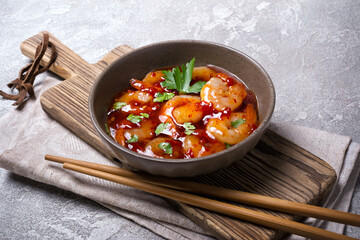 Tasty bright seafood. Bowl of shrimps in spicy asian red sauce with chopsticks
