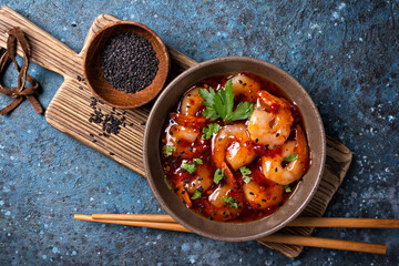 Tasty bright seafood. Bowl of shrimps in spicy asian red sauce with chopsticks