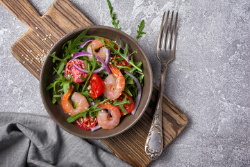 Healthy salad with fresh arugula, cherry tomatoes, tasty shrimps and onion