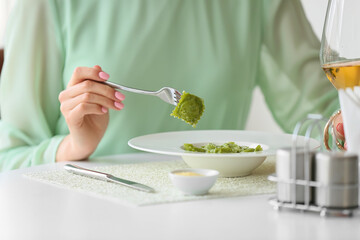 Beautiful young woman eating tasty ravioli in cafe, closeup
