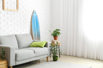 Interior of modern stylish room with surfboard, sofa and houseplants