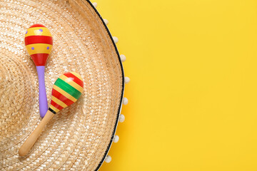 Mexican maracas and sombrero on color background