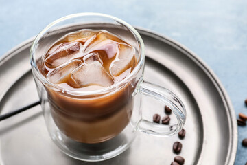 Plate with glass cup of tasty iced coffee on table