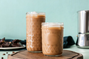 Wooden board with glasses of tasty iced coffee on table