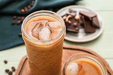 Wooden board with glasses of tasty iced coffee on table, closeup