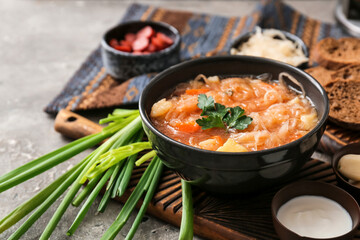 Bowl with tasty sauerkraut soup and sour cream on grunge background