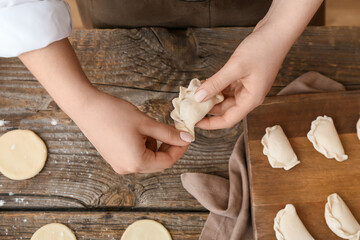 Woman preparing tasty dumplings on kitchen table, closeup