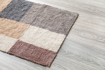 Colorful carpet on wooden floor, closeup