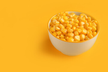 Bowl of corn kernels on color background