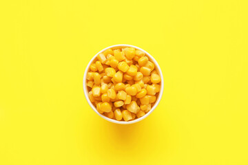 Bowl of corn kernels on color background
