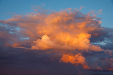 Large fluffy white and orange pink clouds in the sunset light. Evening dawn or sunset sky beautiful background, horizontal