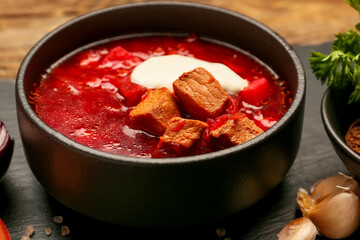 Bowl of tasty borscht with sour cream on table