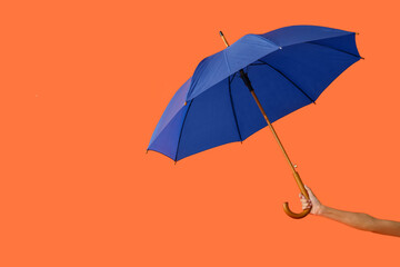 Female hand with open umbrella on color background