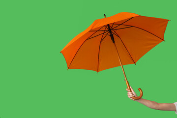 Female hand with open umbrella on color background