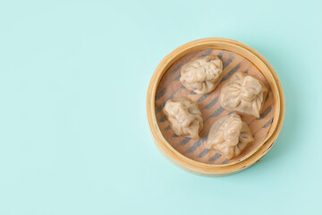 Bamboo steamer with tasty dumplings on color background